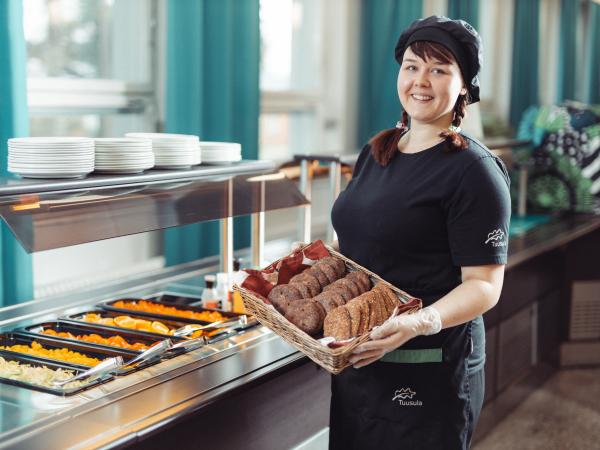 Nainen ruokalinjaston edessä leipäkori kädessä