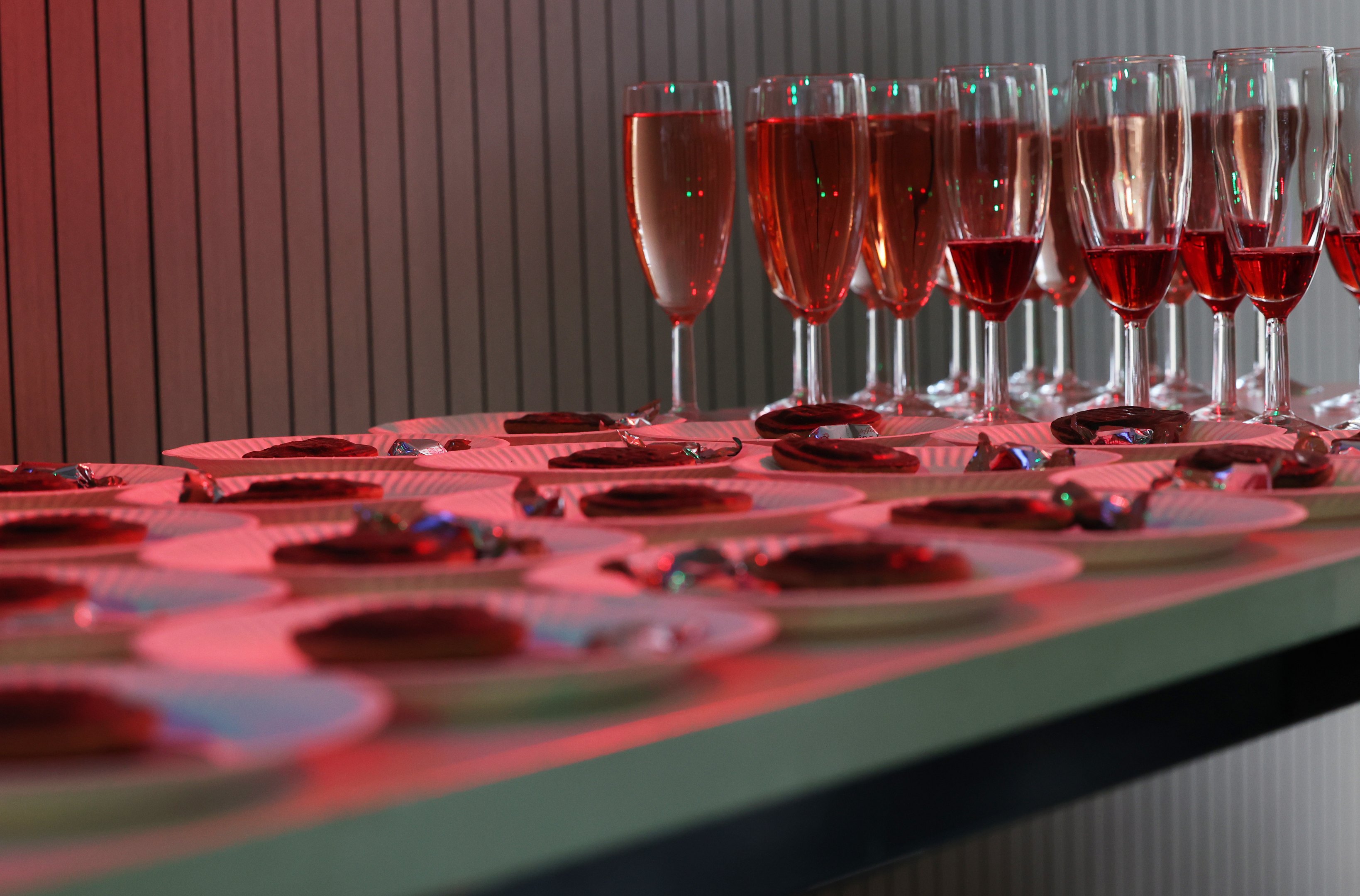 Tarjoilupöytä, jossa on punaista mehua laseissa ja keksi ja karkki lautasella.