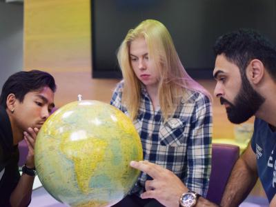 Three students inspecting a globe.