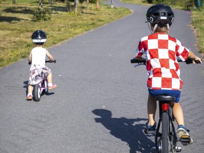 Kaksi pientä lasta ajaa pyörällä.