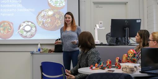 Opiskelija esittelee venäläisiä ruokien nimiä power point -esityksestä, joka on heijastettu valkokankaalle.