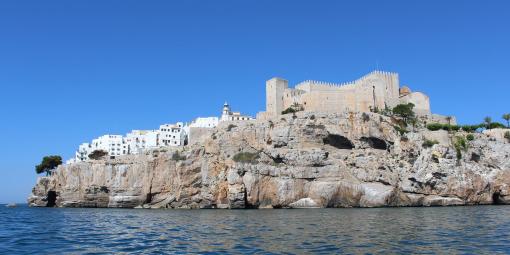 Näkemä Välimereltä jyrkälle kalliorinteelle, jonka päällä on linna ja taloja.
