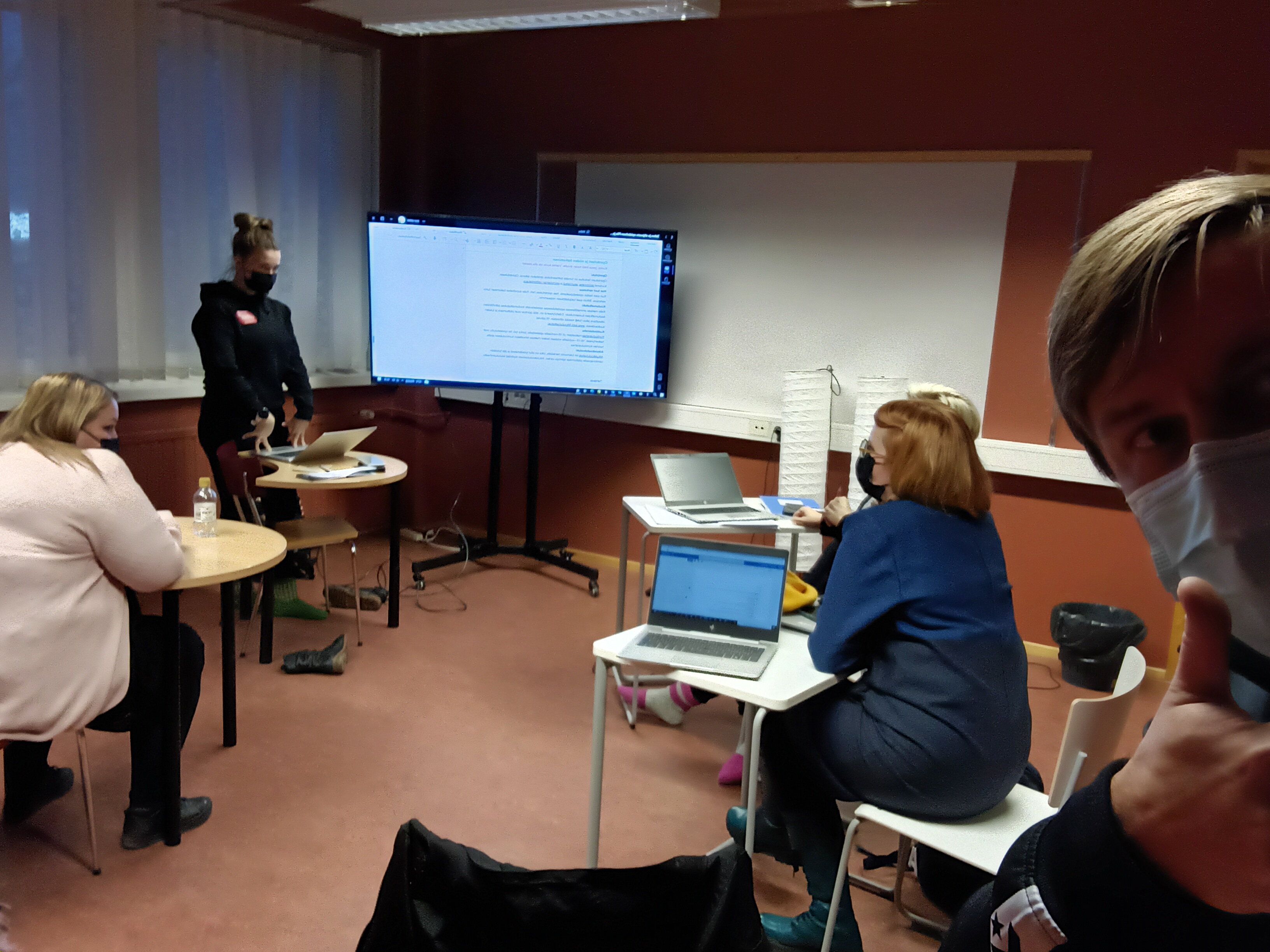 Selfie neljän henkilön pienryhmätyökentelystä pienestä luokkatilasta. Etualalla kuvan ottaja eli kirjoittaja näyttää peukkua.