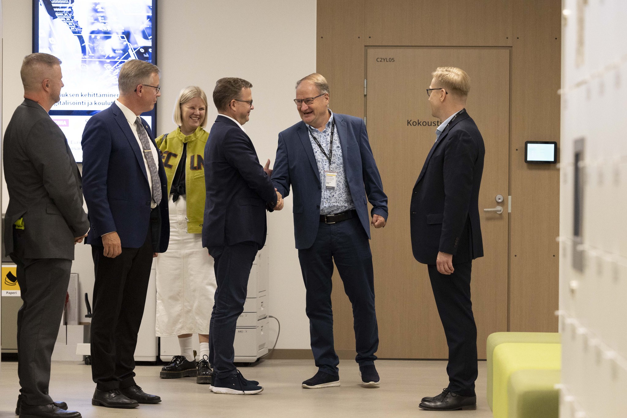Joukko ihmisiä kättelee.