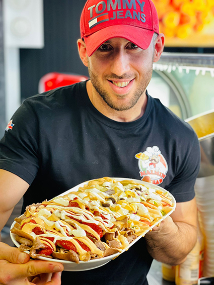 mies lippalakki päässä ja pizza kädessä