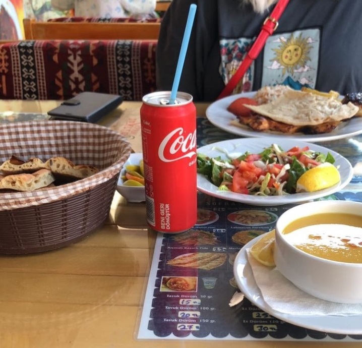 Lounaspöydässä keitto salaattilautanen ja Coca-Cola-purkki.