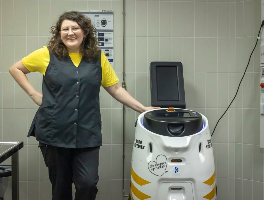 Henkilö nojaa siivousrobottiin.