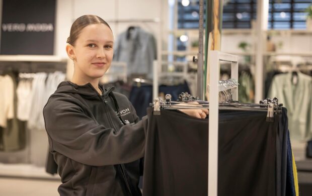 Opiskelija laittaa housuja henkareihin myytäväksi.