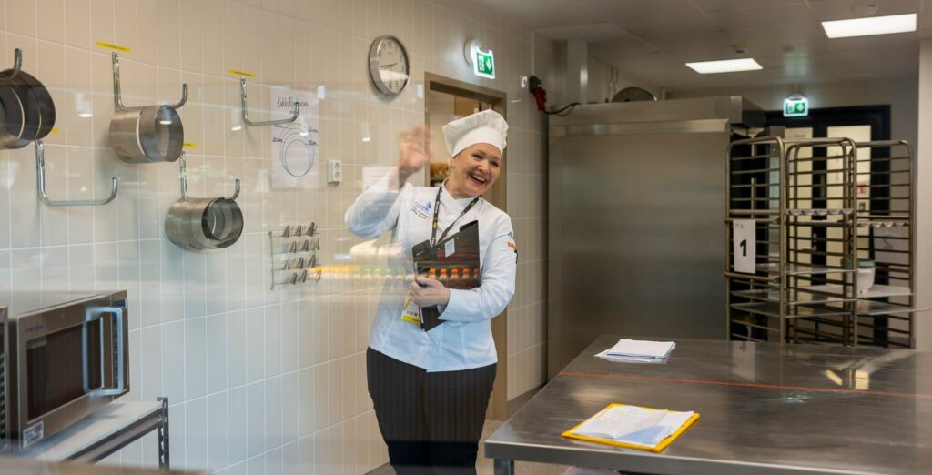 iloinen kokki vilkuttaa leipomossa.