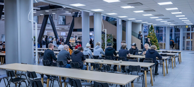 Aulassa istuu ihmisiä pöydän ääressä.