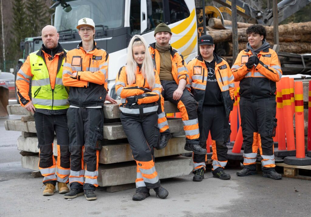 Opiskelijaryhmä kuorma-auton edessä. Kaikilla huomioasut yllä.