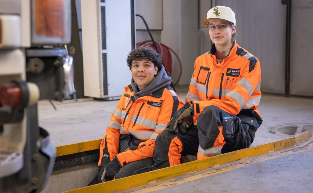 Kaksi poikaa istuu logistiikan hallissa.