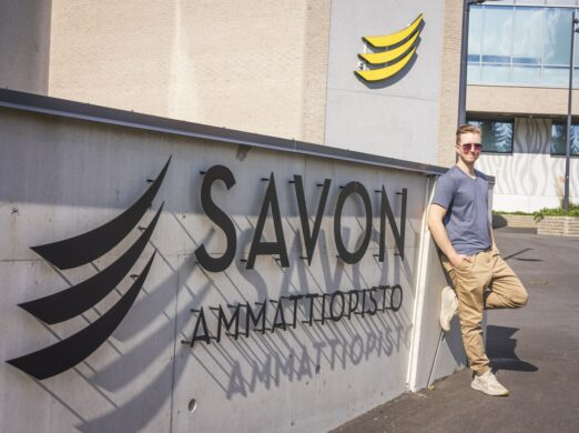 Savon ammattiopisto lukee kohokirjaimin seinässä ja mies nojaa seinään.