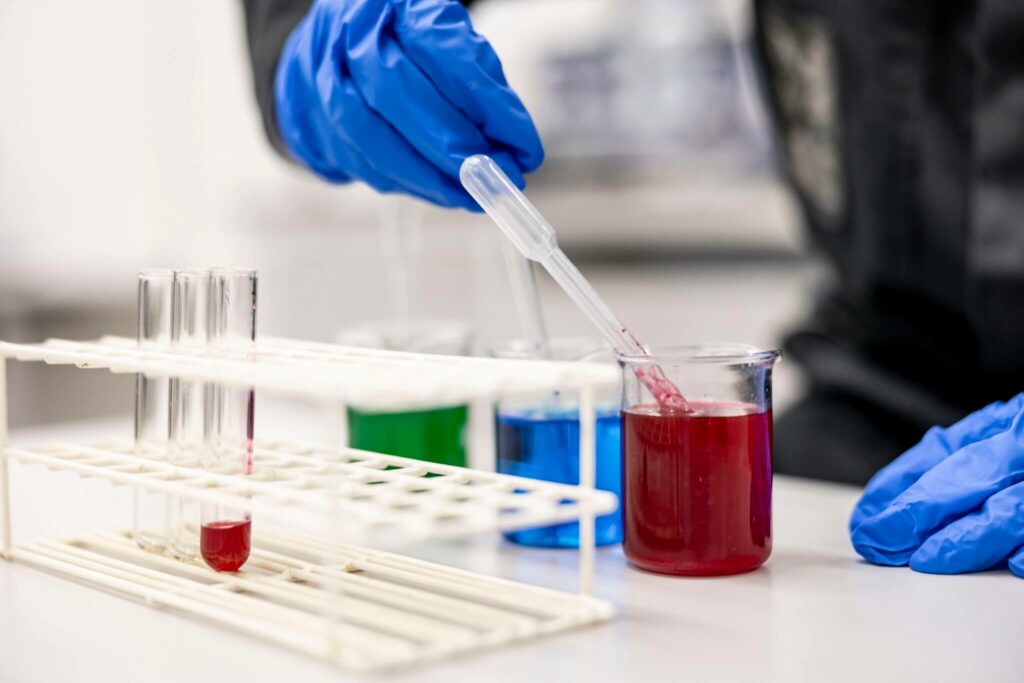 pipetillä laitetaan punaista liuosta mittalasissa.