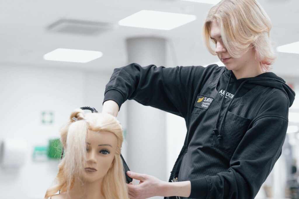 Opiskelija kampaa harjoituspään hiuksia.