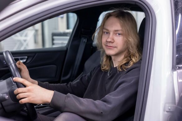 mies istuu auton sisällä ja pitää käsiään auton ratissa.