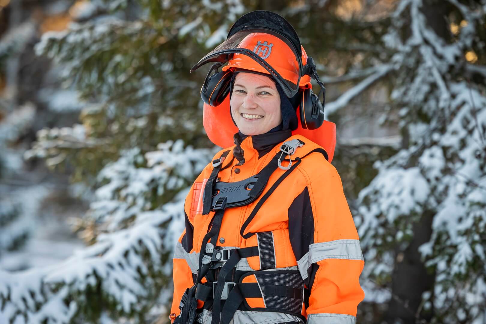 Opiskelijalla on yllään huomioasu ja kypärä. Hän hymyilee.
