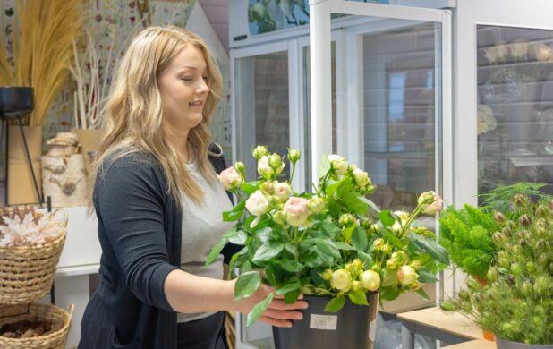 Nainen asettelee kukkia maljakkoon.