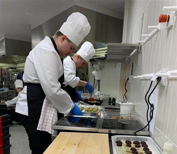 Kaksi kokkiopiskelijaa valmistaa annoksia.