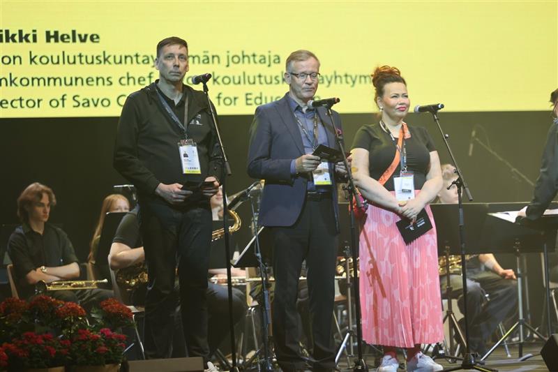Petteri Makkonen Heikki Helve ja Sanna Kauppinen seisovat lavalla.
