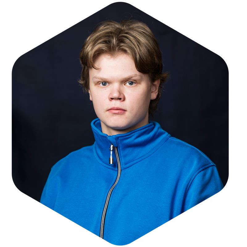 Nuori ruskeatukkainen mies sinisessa takissa katsoo kameraan vakavaka. Tumma tausta.