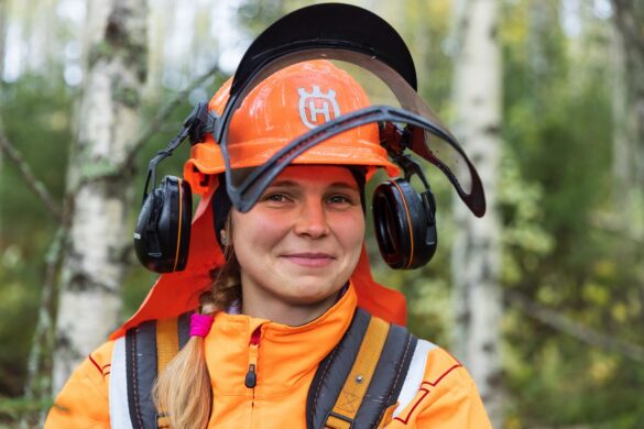 Ihminen metsurin vaatteet ja kypärä päässä hymyilee kameralle.