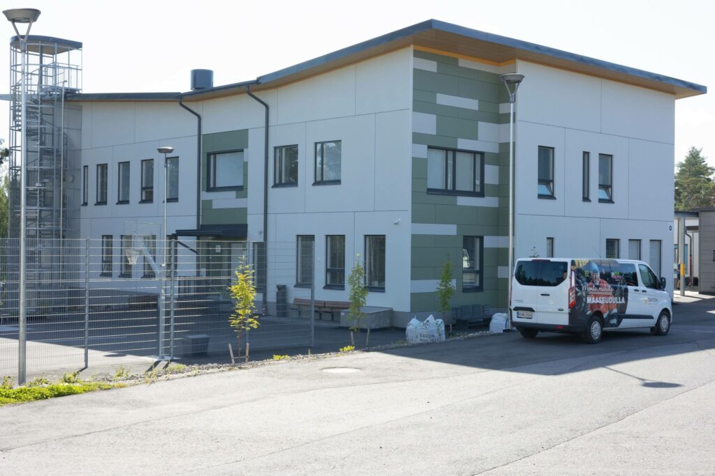 Toivalan kampuksen valkoinen piharakennus ja talon edessä pakettiauto