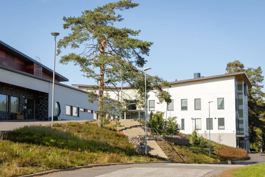 Toivalan kampuksen valkoinen rakennus ja pihapuu kesällä