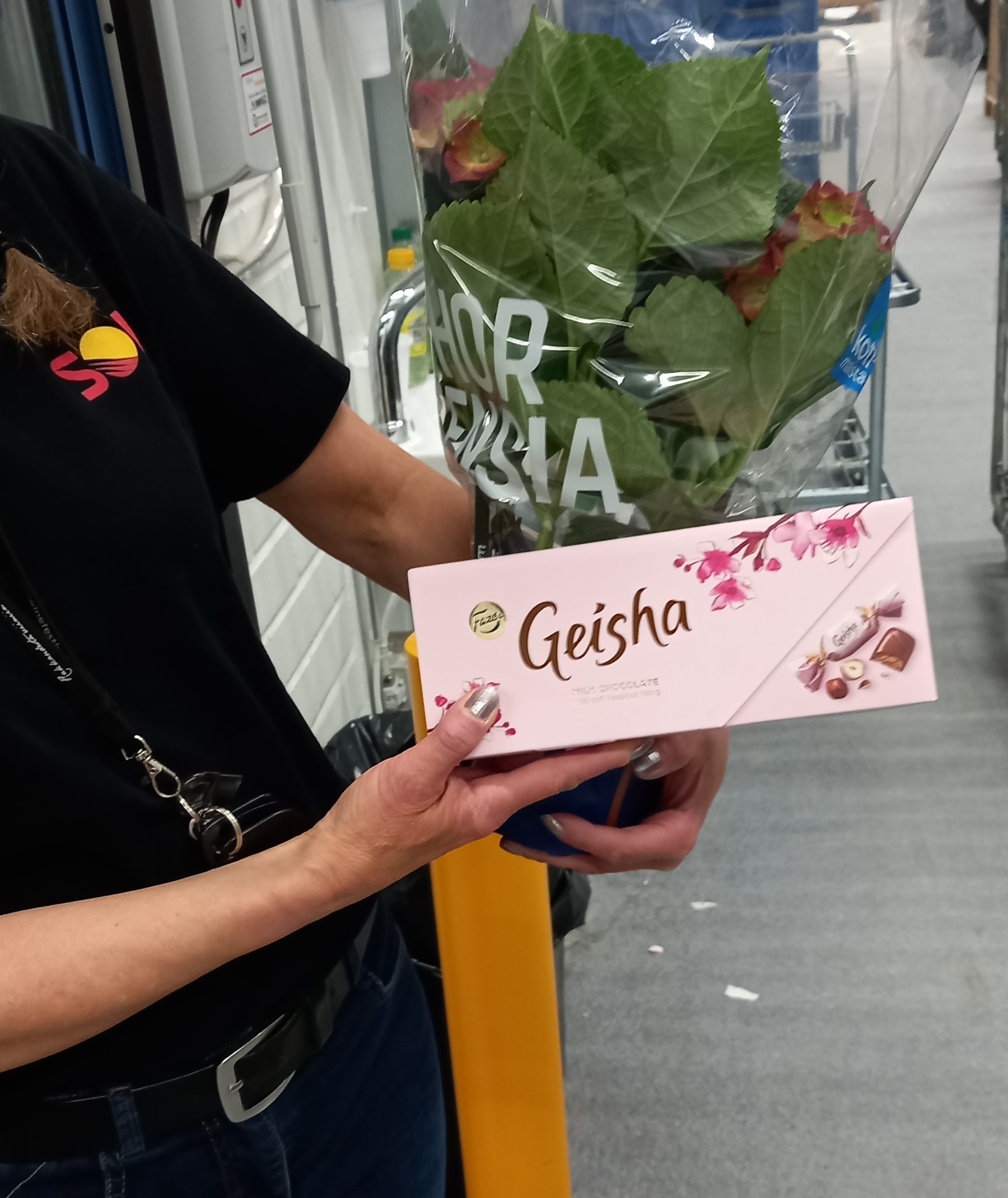 Geisha-rasia ja kukkapuska opiskelijan kädessä. Opiskelijan kasvoja ei näy.