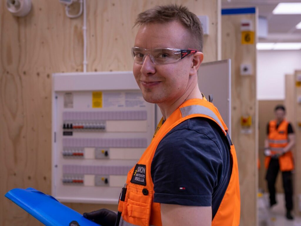 suojalasit päässä oleva opiskelija hymyilee kameralle.