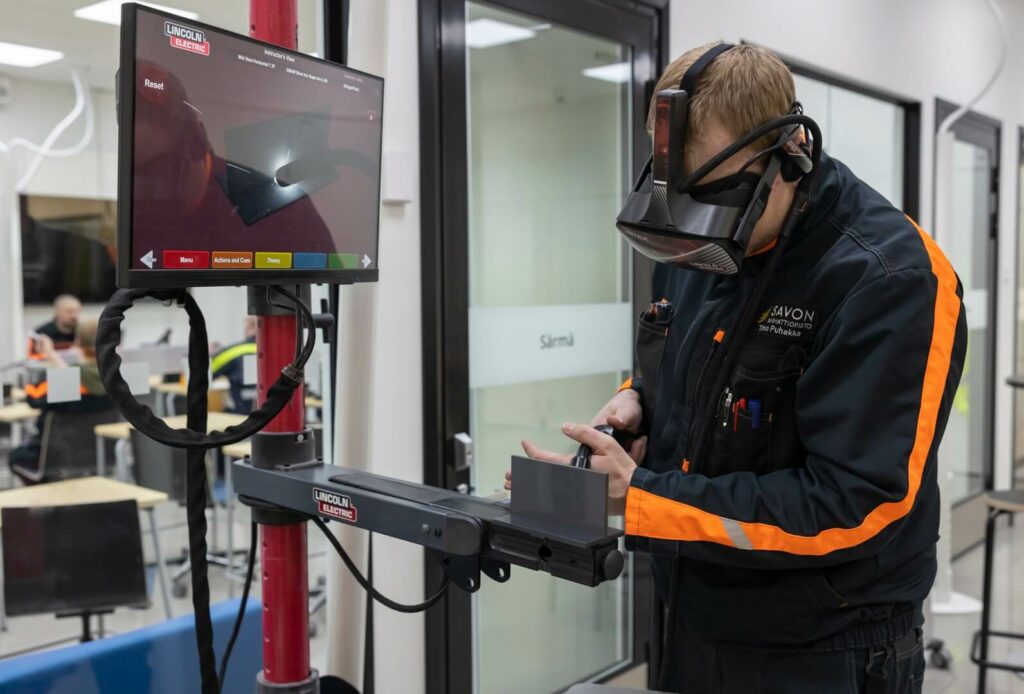 Opiskelija harjoittelee virtuaaliset lasit päässä hitsausta.