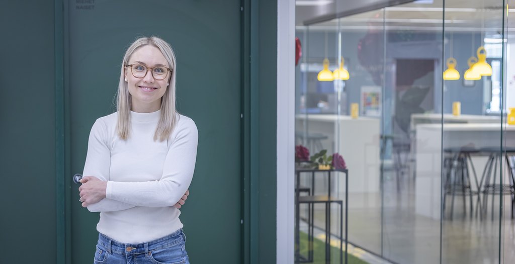 Ihminen seisoo ja katsoo hymyillen kameraan.