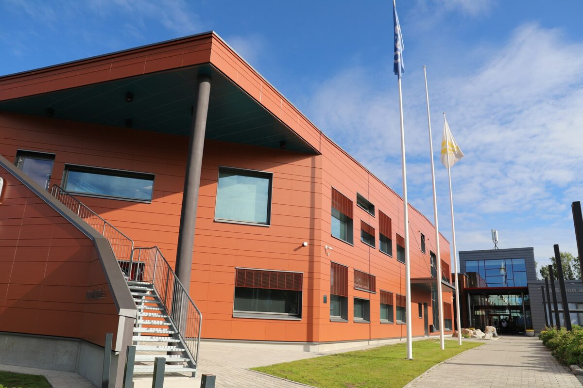 Punainen iso rakennus kauniina kesäpäivänä.