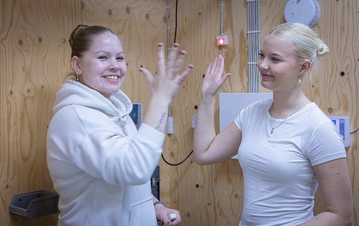 Opiskelijat läpsäyttävät käsiä yhteen ja hymyilevät.