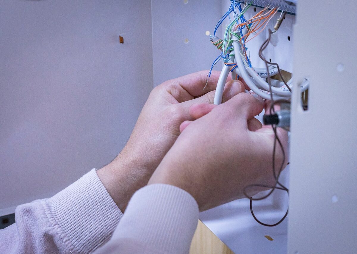 Kädet asettavat sähköjohtoja hälyttimeen.