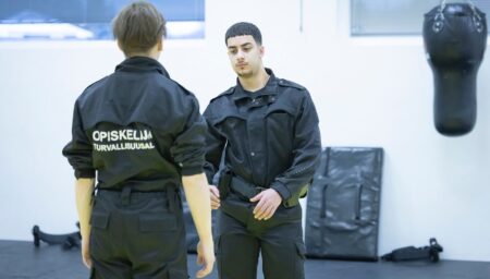Kaksi opiskelijaa työhaalareissa harjoittelemassa voimankäyttöä.
