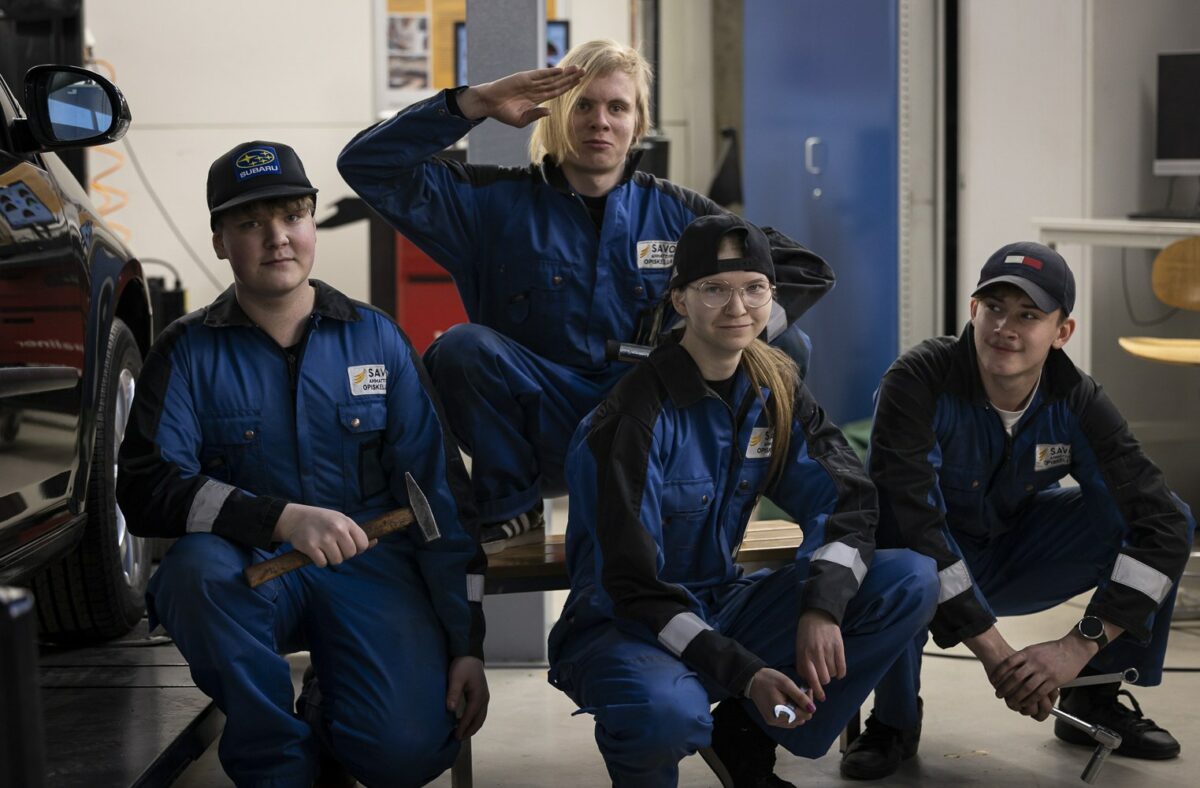 Neljä opiskelijaa on kyykyssä ja katsovat kameraan.