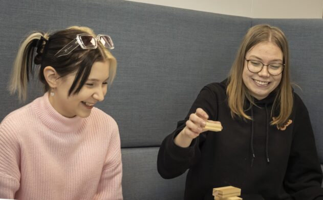 Kaksi opiskelijaa nauravat sohvalla.