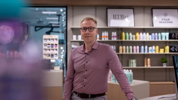 Asiakas on myymälässä ja katsoo kameraan.