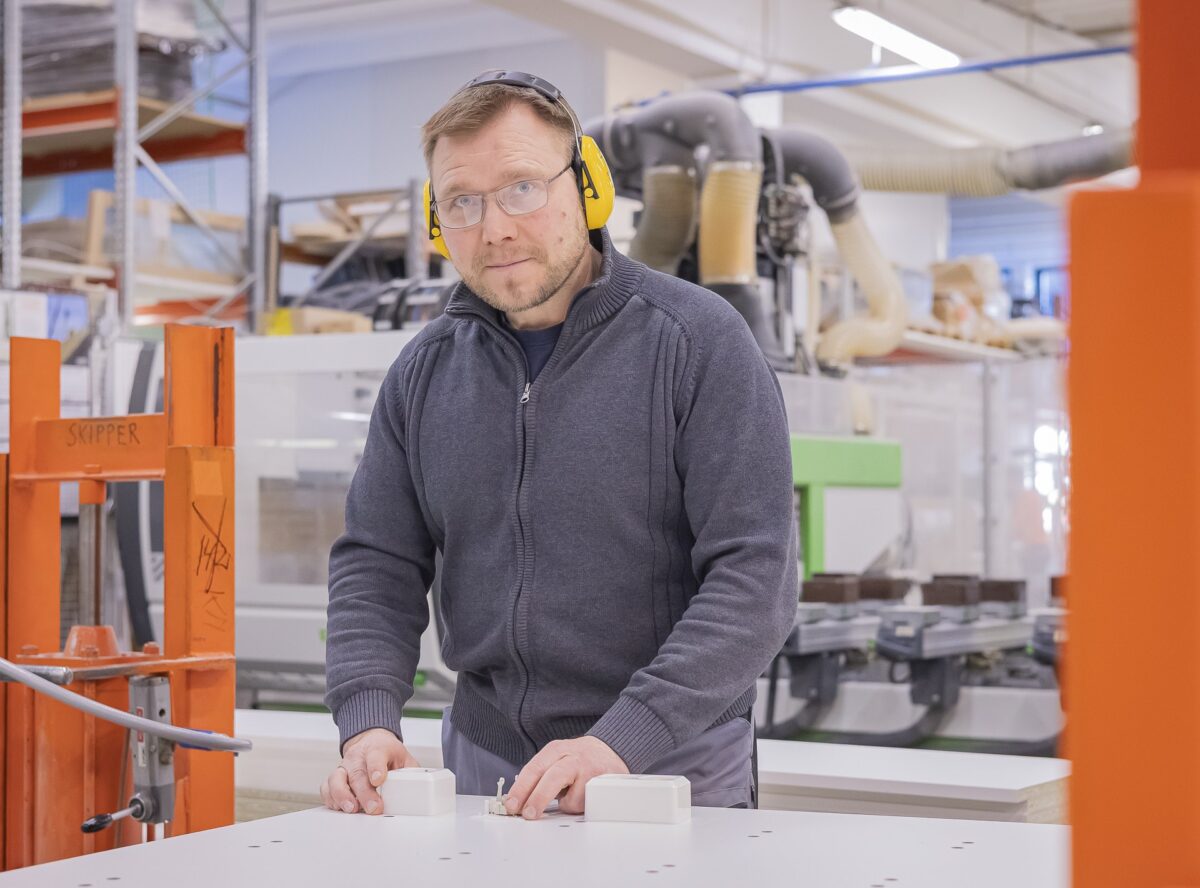 Ihminen, jolla on kuulosuojaimet, katsoo kameraan.