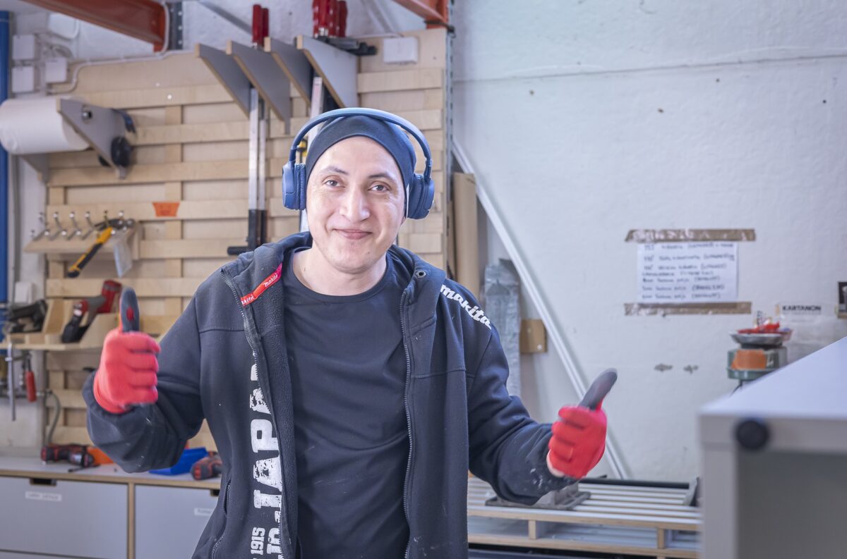 Ihminen, jolla on kuulokkeet, näyttää peukkuja.