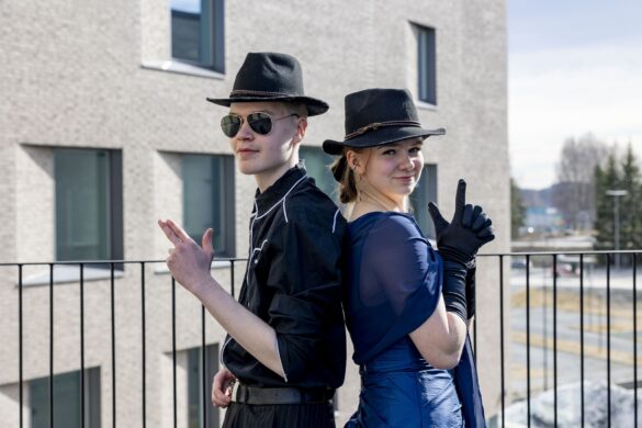 Opiskelijat hatut päässään ja selät vastaikkain.