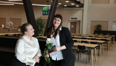 Opiskelija on saanut ruusun ja opettaja katsoo ylpeänä.
