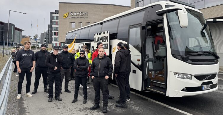 Ihmisiä seisoo linja-auton sivulla.