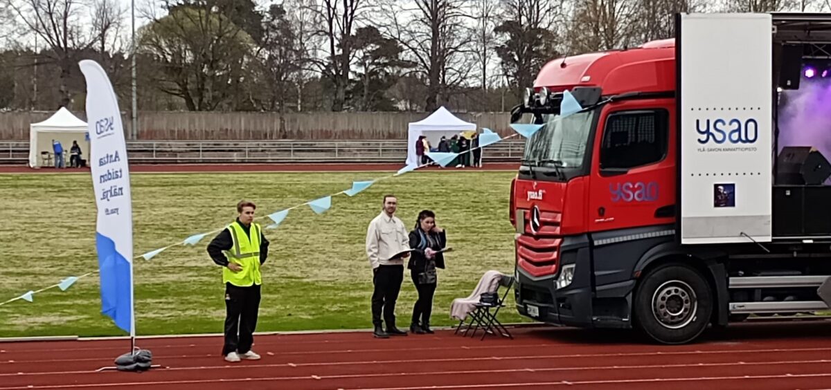 Urheilukenttä, jossa on rekka ja ihmisiä.