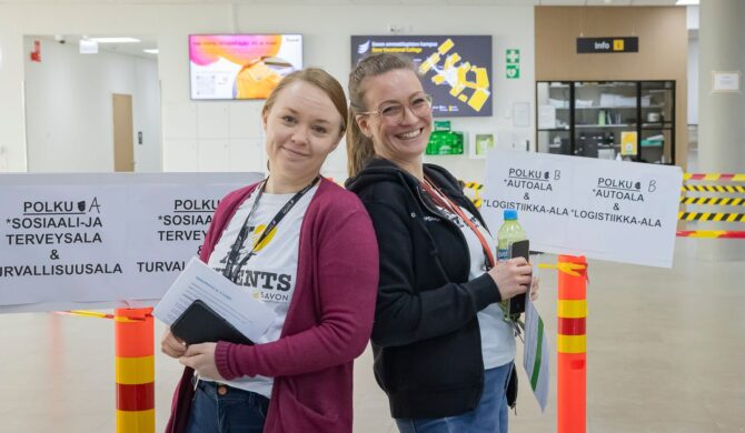 Kaksi iloista henkilöä katsoo kameraan ja hymyilee iloisesti.